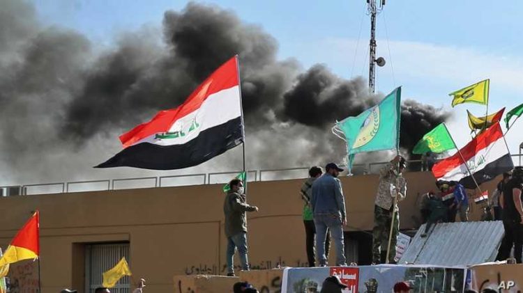 Smoke rises after pro-Iranian militiamen and their supporters set a fire in front of the U.S. embassy in Baghdad, Iraq, Wednesday, Jan. 1, 2020. U.S. troops have fired tear gas to disperse hundreds of pro-Iran militiamen and other protesters who were gathered for a second day outside the American Embassy compound in Baghdad. (AP Photo/Khalid Mohammed)