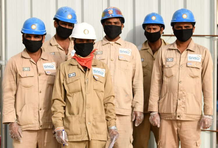 Indian men working for a public services company in the United Arab Emirates, pose for a picture with their protective gear, masks and gloves, during the coronavirus COVID-19 pandemic, in Dubai on April 2, 2020. (Photo by KARIM SAHIB / AFP) (Photo by KARIM SAHIB/AFP via Getty Images)