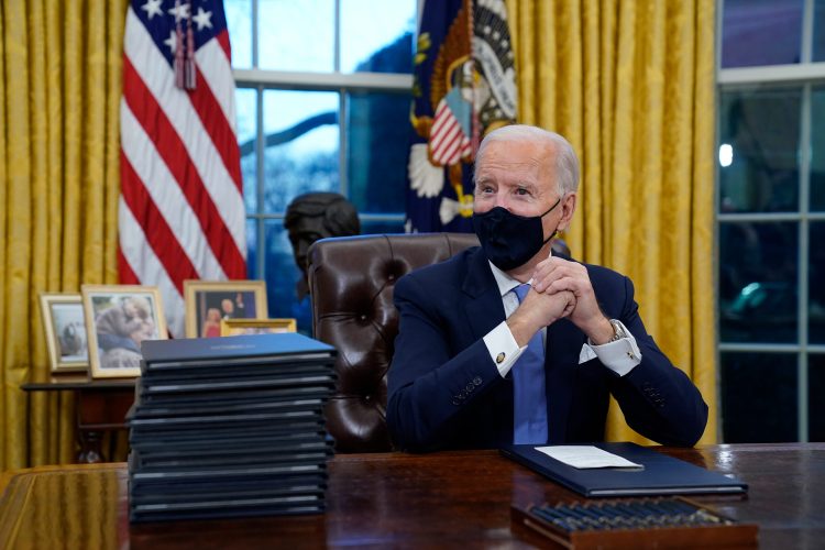President Joe Biden waits to sign his first executive order in the Oval Office of the White House on Wednesday, Jan. 20, 2021, in Washington. (AP Photo/Evan Vucci)