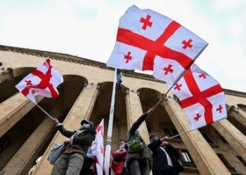 Georgian opposition supporters wave the national flag during a rally in central Tbilisi on November 14, 2020. - Georgian opposition supporters vow permanent protest rallies -- despite a violent police crackdown -- until snap polls are called as the opposition accused the ruling Georgian Dream party of rigging legislative elections, which it won narrowly a week ago. (Photo by Vano SHLAMOV / AFP)