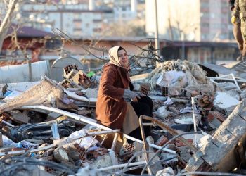 A woman sits on the rubble of a destroyed building in Kahramanmaras, southern Turkey, a day after a 7.8-magnitude earthquake struck the country's southeast, on February 7, 2023. - Rescuers in Turkey and Syria braved frigid weather, aftershocks and collapsing buildings, as they dug for survivors buried by an earthquake that killed more than 5,000 people. Some of the heaviest devastation occurred near the quake's epicentre between Kahramanmaras and Gaziantep, a city of two million where entire blocks now lie in ruins under gathering snow. (Photo by Adem ALTAN / AFP) (Photo by ADEM ALTAN/AFP via Getty Images)