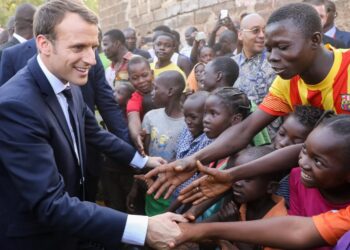 French President Emmanuel Macron shakes hands with children after visiting the Lagm Taaba school on November 28, 2017, in Ouagadougou, as part of his first African tour since taking office. / AFP PHOTO / ludovic MARIN