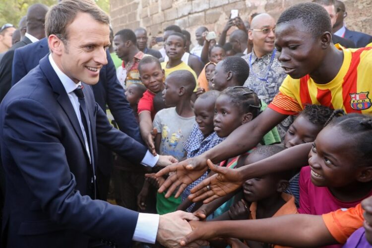 French President Emmanuel Macron shakes hands with children after visiting the Lagm Taaba school on November 28, 2017, in Ouagadougou, as part of his first African tour since taking office. / AFP PHOTO / ludovic MARIN