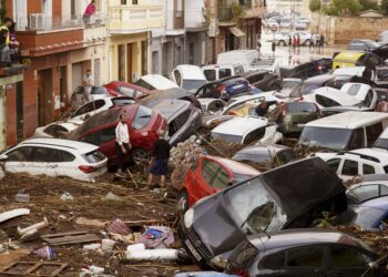 Residents look at cars piled up after being swept away by floods in Valencia, Spain, Wednesday, Oct. 30, 2024. (AP Photo/Alberto Saiz)